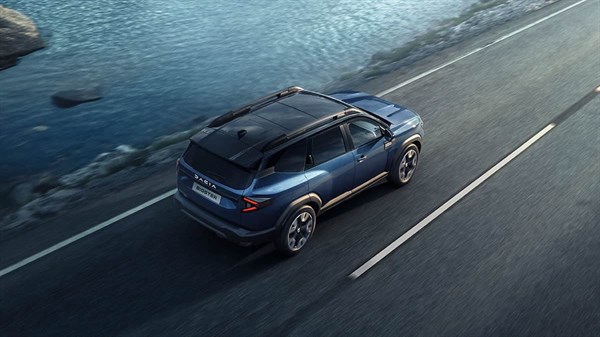 מבט מאחור מגבוה על דאצ'יה ביגסטר בנסיעה בכביש לצד הים